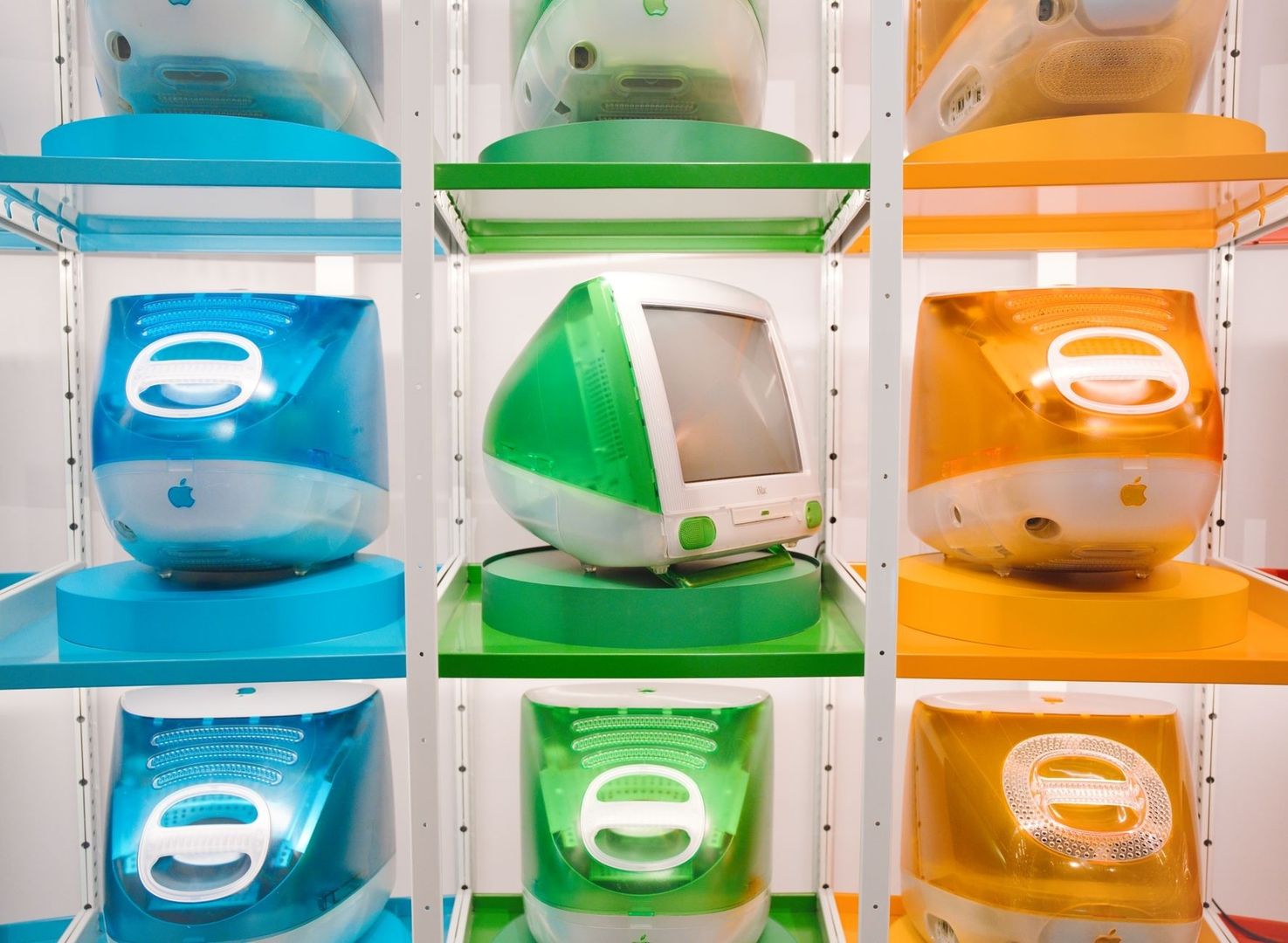 Colorful vintage Apple computers displayed on museum shelving
