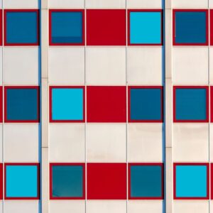 Geometric building facade with a repeated grid of red panels and blue windows