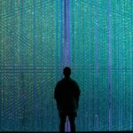 Silhouette facing a wall of colorful, grid-like digital lights